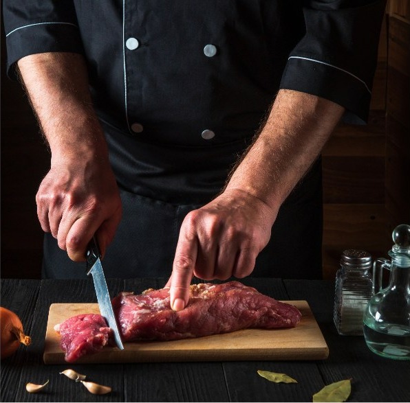 Macellaio al lavoro mentre taglia la carne